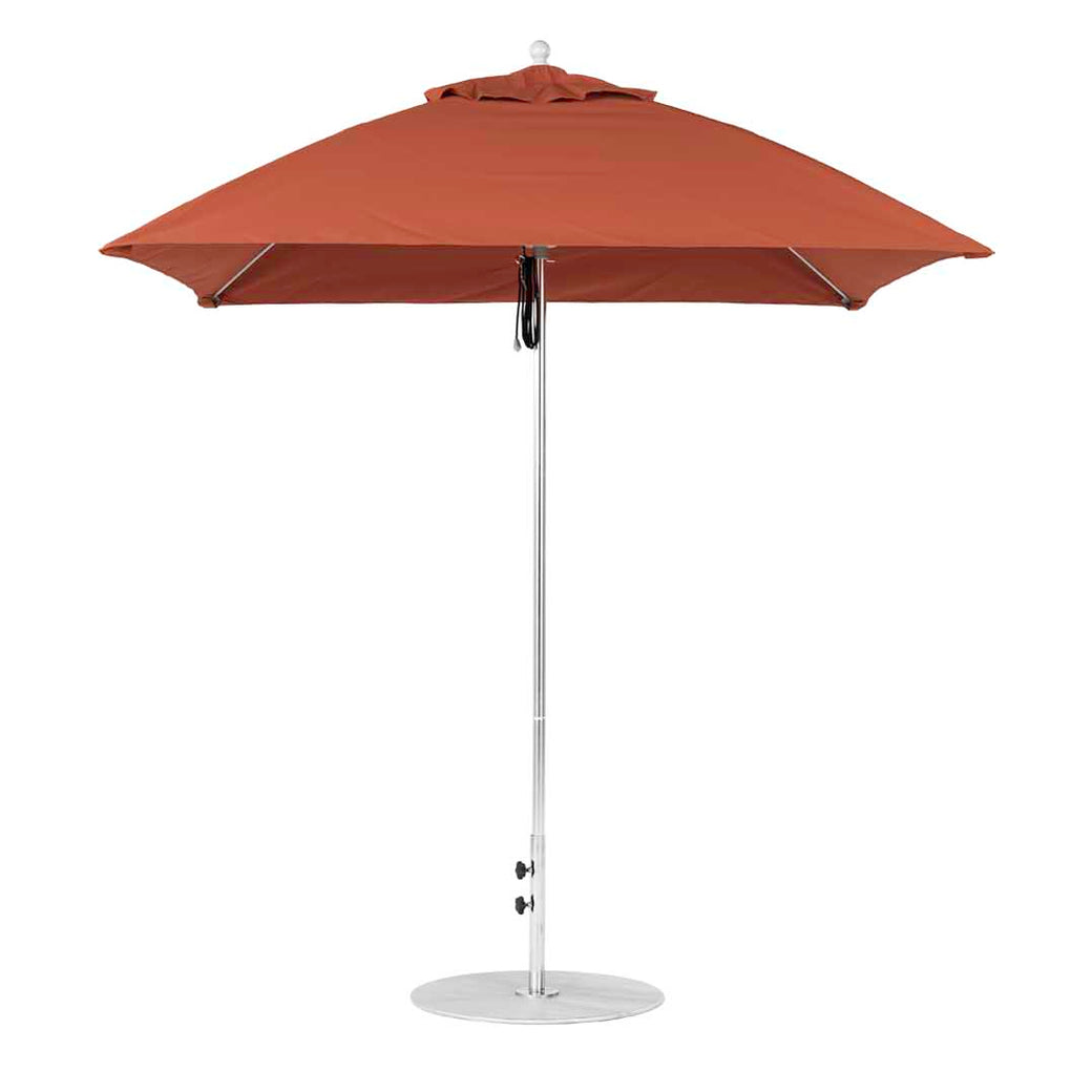 The Essential Fiberglass Umbrella - 7.5 Square Pulley by Ledge Lounger stands upright, its vibrant red marine-grade fabric canopy fully open on a silver pole with neat stitching and supported by a round metal base against a white background.