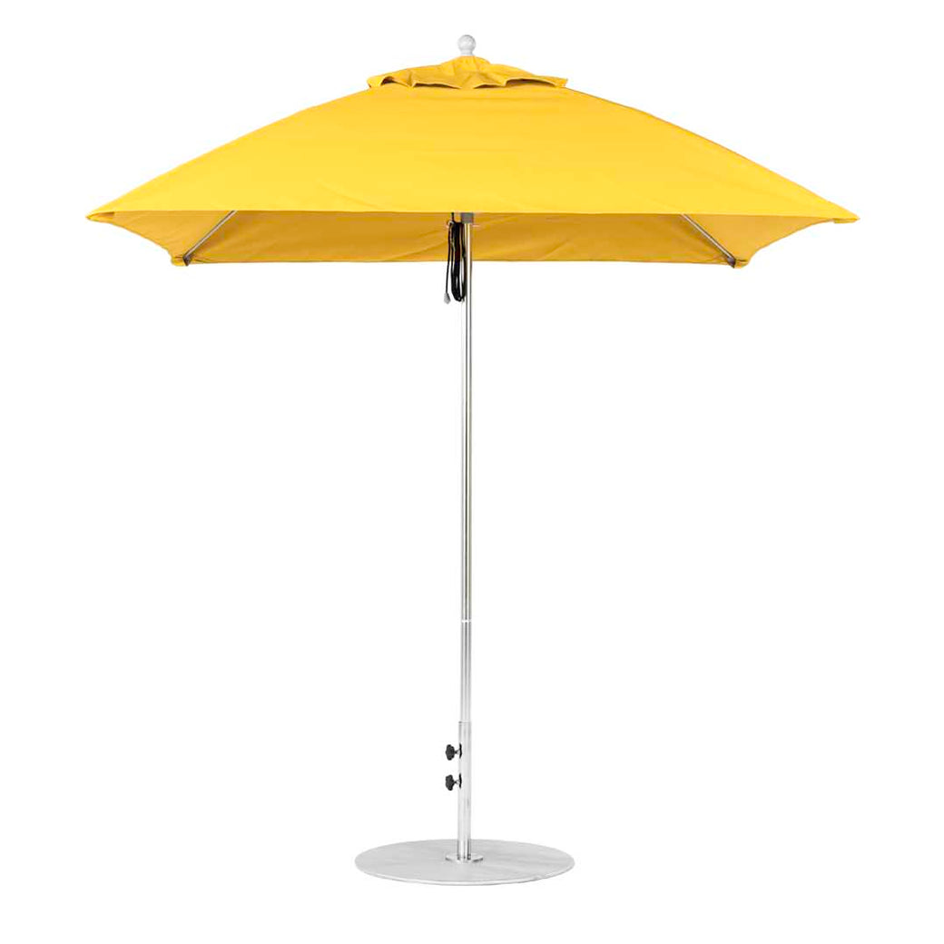 The closed yellow Essential Fiberglass Umbrella - 7.5 Square Pulley by Ledge Lounger stands on a sleek metallic pole with a round base. Built from marine-grade fabrics, its vibrant canopy is neatly folded, ideal for both in-pool and on-deck use.