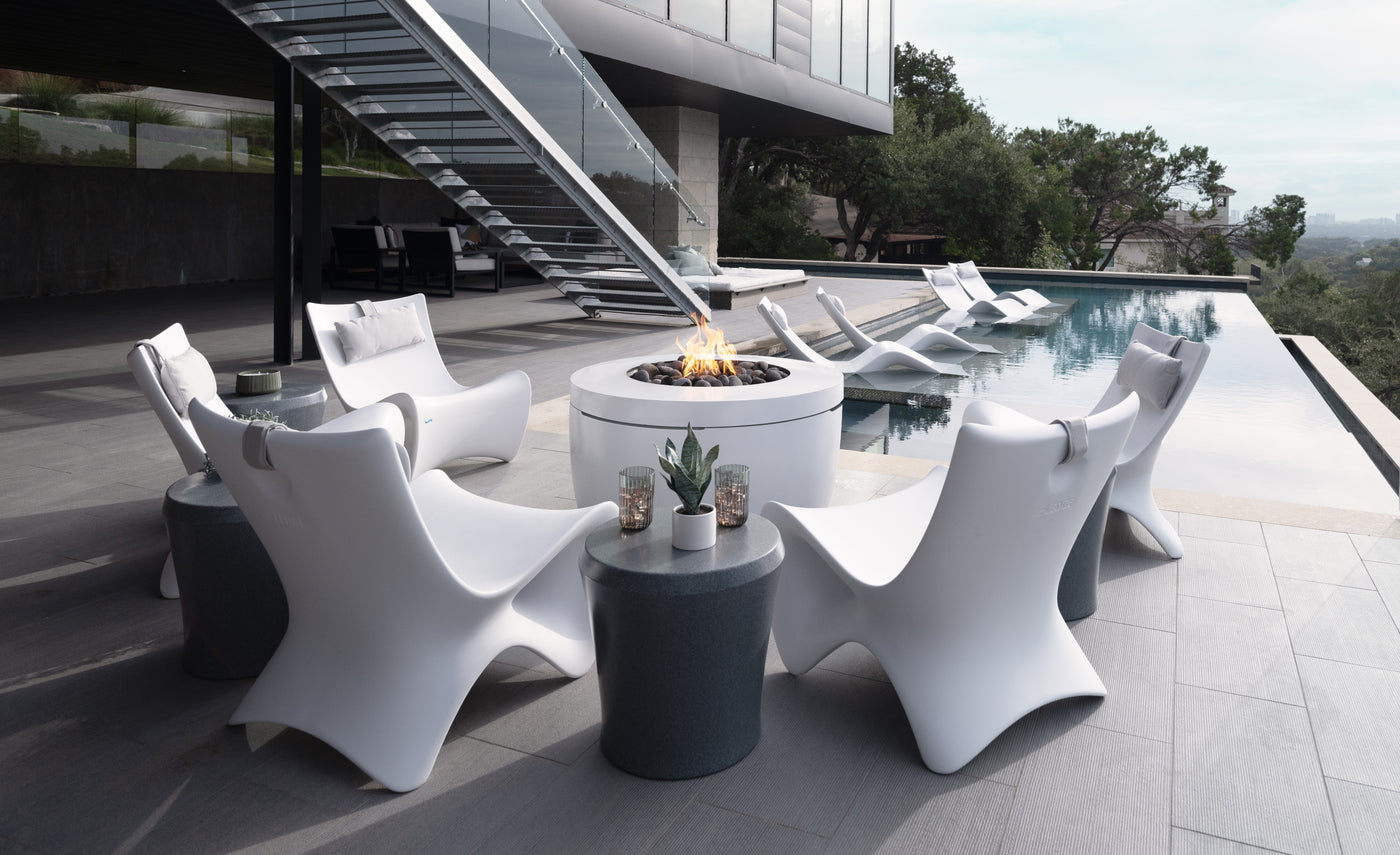 Modern outdoor furniture set with a fire pit by a poolside.
