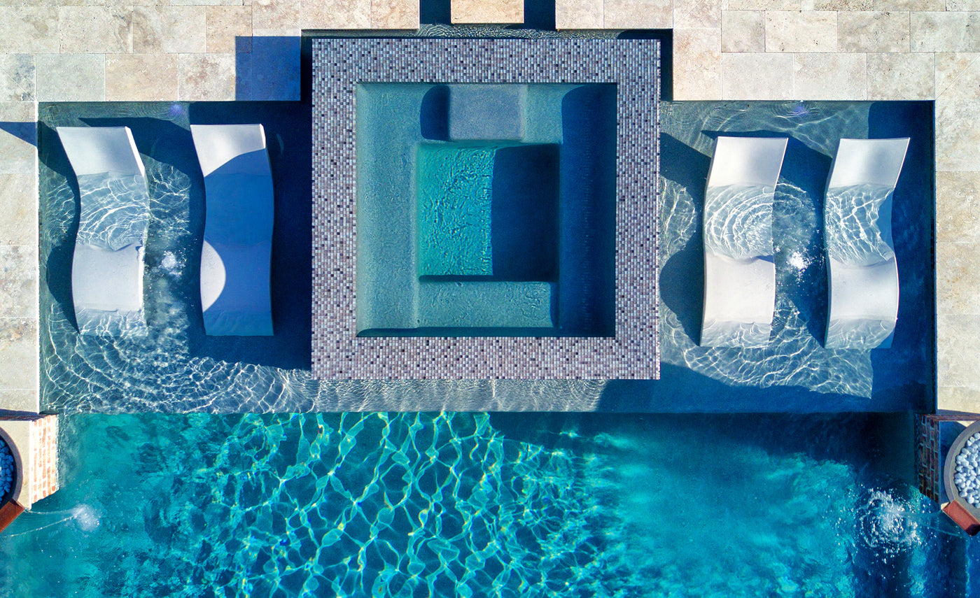Aerial view of a swimming pool with lounge chairs and a spa.