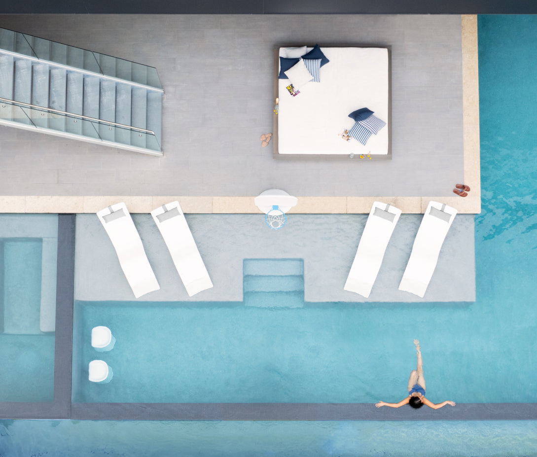 Top-down view of a pool area with lounge chairs and a person diving in.