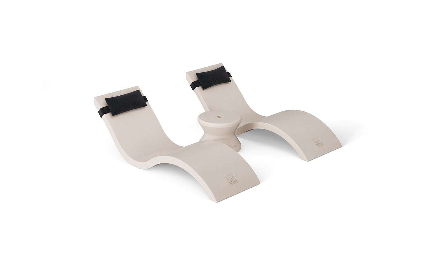 The Ledge Lounger Outdoor Paradise In-Pool Furniture Bundle features a cream-colored, abstract double-seat bench with black cushion-like backrest elements and a central elevated curve, creating a modern artistic vibe. Perfect for any outdoor paradise, it is displayed against a plain white background.