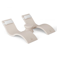 Two modern beige outdoor lounge chairs with curved designs and white headrest cushions grace a white background. Arranged in an S-shape with a circular table between, they epitomize pool ledge furniture elegance from Ledge Loungers Outdoor Paradise In-Pool Furniture Bundle.