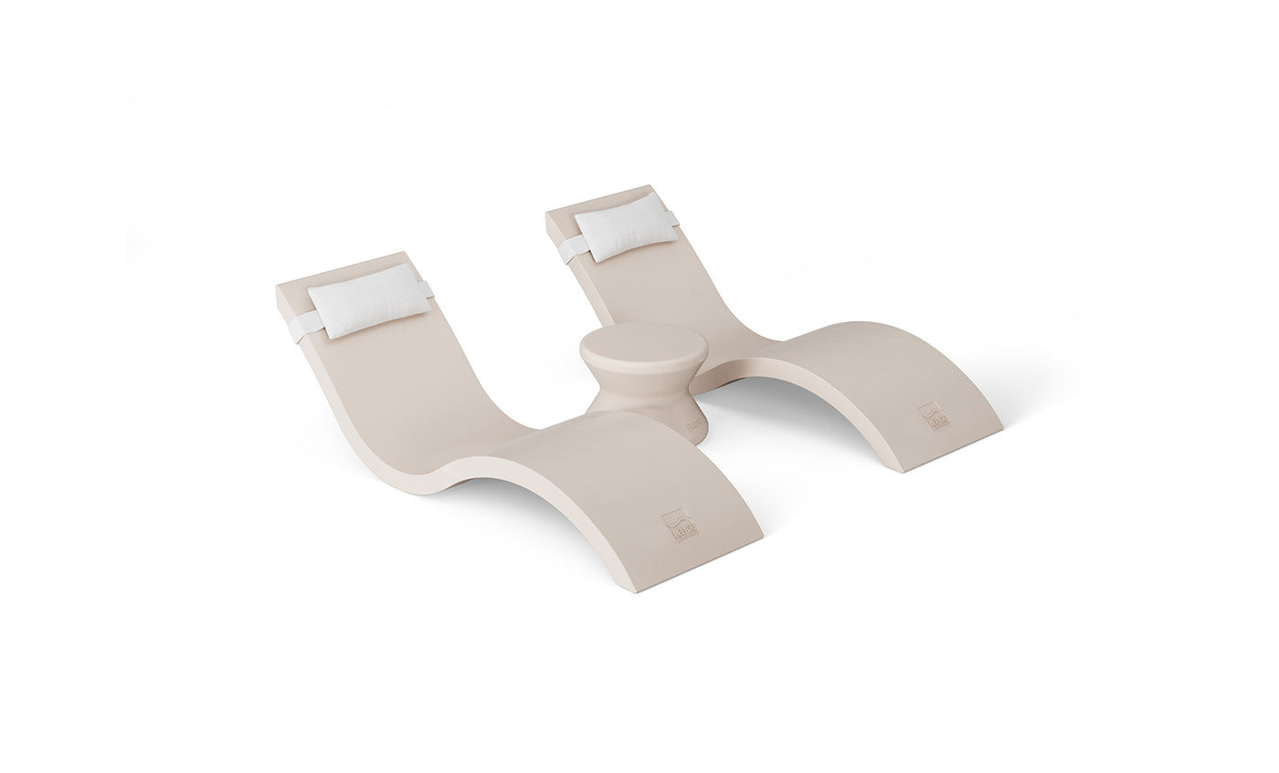Two modern beige outdoor lounge chairs with curved designs and white headrest cushions grace a white background. Arranged in an S-shape with a circular table between, they epitomize pool ledge furniture elegance from Ledge Loungers Outdoor Paradise In-Pool Furniture Bundle.