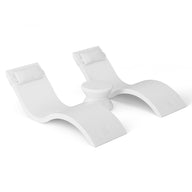 The Outdoor Paradise In-Pool Furniture Bundle by Ledge Lounger features two modern white chaise loungers with headrests side by side, separated by a small table. With smooth, curved lines on a solid white background, its the perfect pool ledge furniture setup.