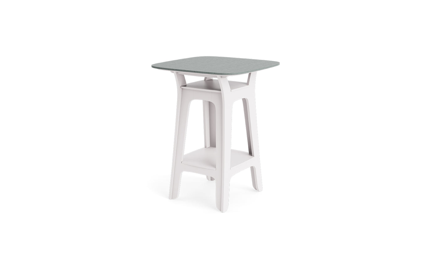 The Haven Hightop Table by Ledge Lounger features a modern, square light grey top, white angled legs, and a lower storage shelf. Its minimalist design brings contemporary style to any outdoor area.