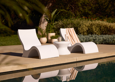 Modern outdoor lounge chairs by a pool with a scenic background