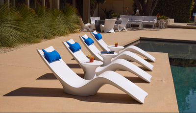 White lounge chairs with blue cushions by a poolside