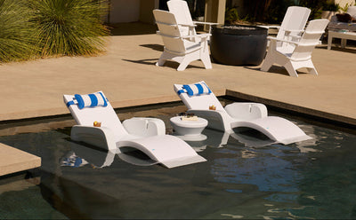 White lounge chairs with blue and white striped cushions by a poolside.